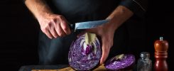 Couteau de chef polyvalent utilisé pour émincer des légumes sur une planche en bois.