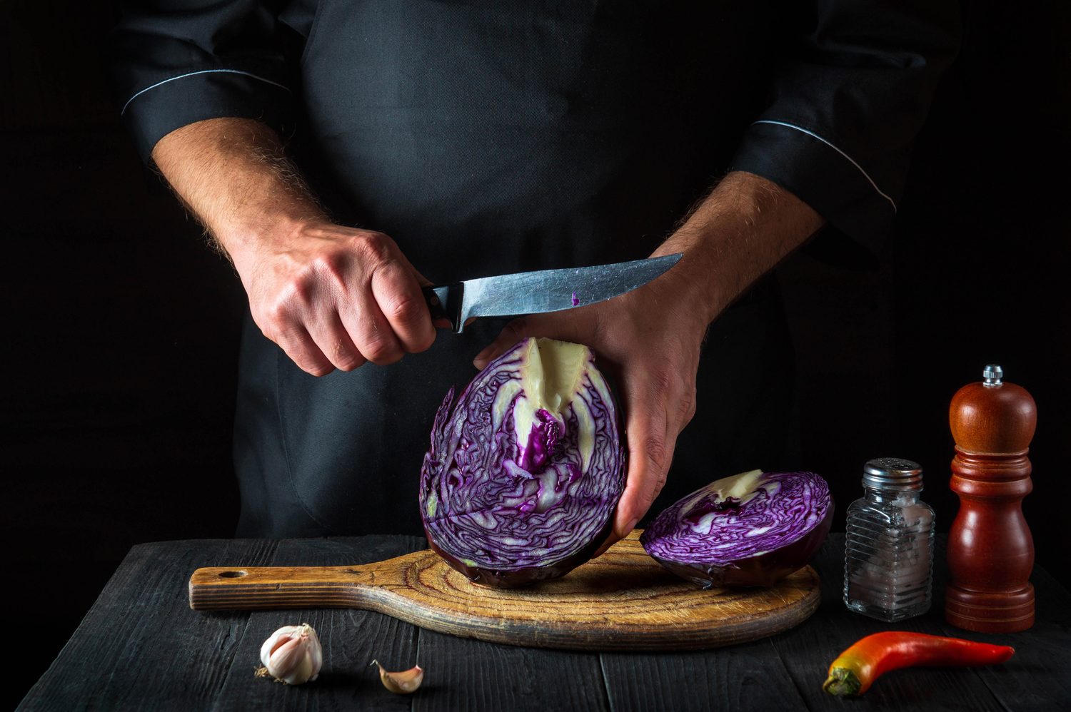 Couteau de chef polyvalent utilisé pour émincer des légumes sur une planche en bois.