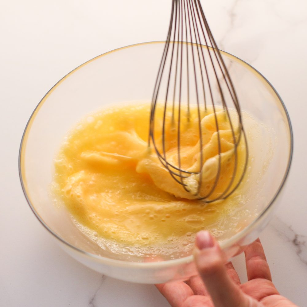 Fouet plongé dans une pâte à crêpes avec des grumeaux, prête à être rattrapée.